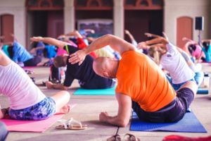 A class of Yoga students do seated side bends. 