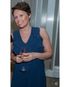A well-dressed woman at a business event holding a glass of champagne